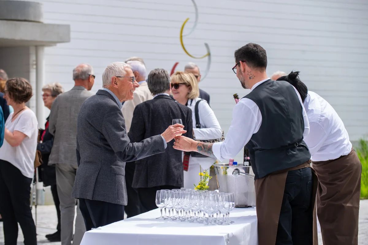 Mehrere Menschen stehen zusammen und reden und lachen. 